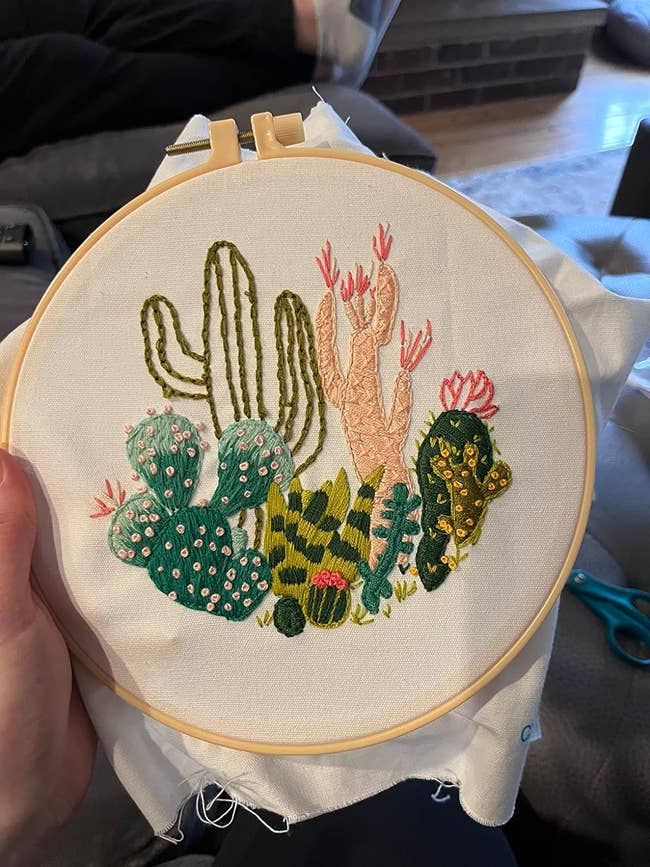 Hand embroidery of assorted cacti on fabric, held in a round hoop