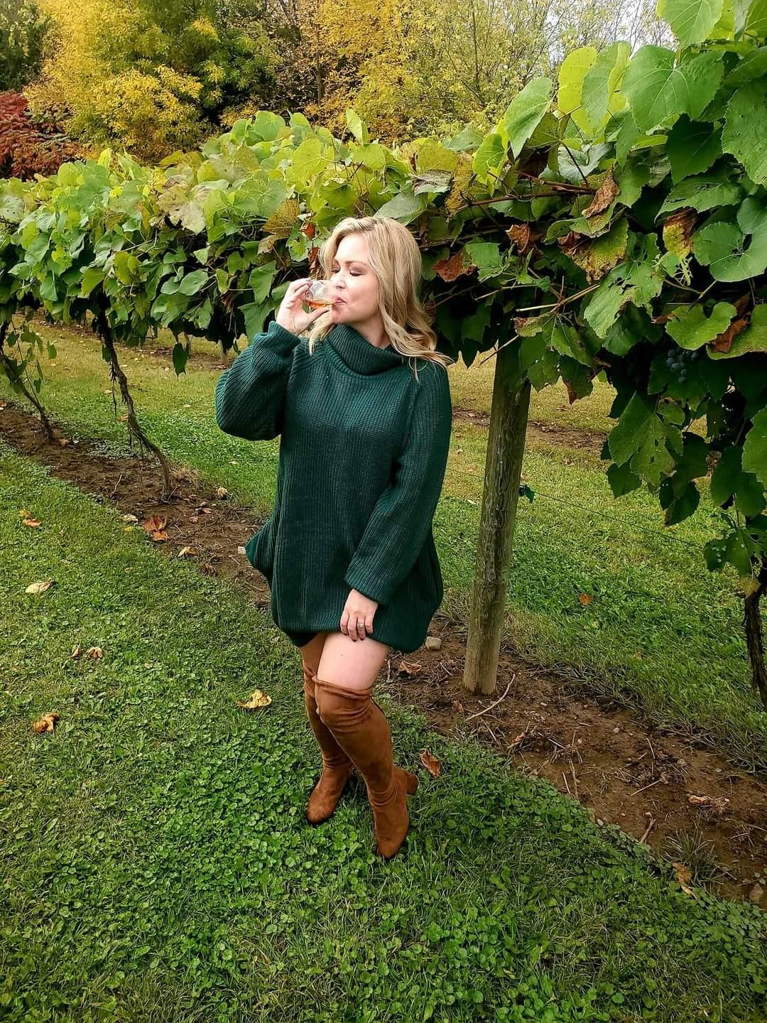 reviewer wearing the dark green sweater dress at a winer