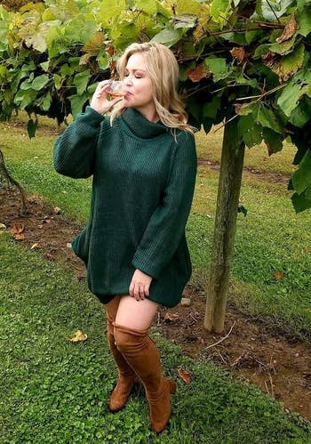 reviewer wearing the dark green sweater dress at a winer