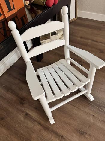 Wooden rocking seat with slatted spot and backrest, positioned indoors connected a woody floor
