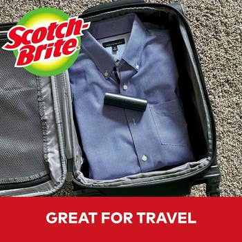 A neatly packed button-up shirt in a suitcase with a lint roller