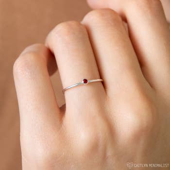 model wearing thin silver ring with tiny ruby