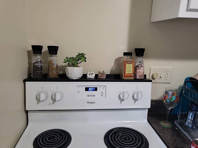 Reviewer's white oven with black shelf on top holding a small plant and some spices