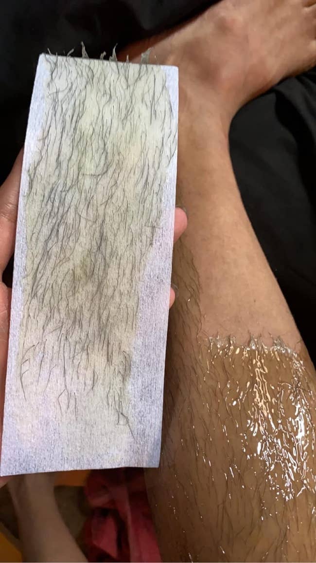 reviewers leg with wax on it holding a strip of hair they waxed off