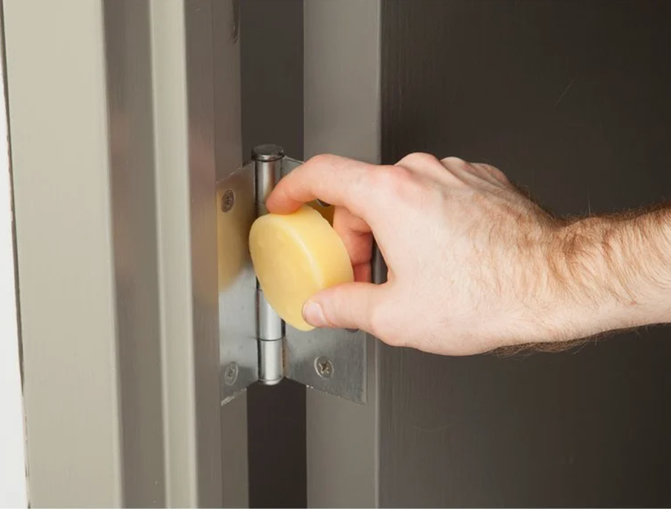 Model using a small round yellow puck of beeswax on a door hinge 