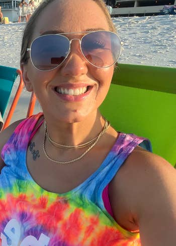 Person smiling successful sunglasses and a tie-dye vessel top, sitting connected a formation chair