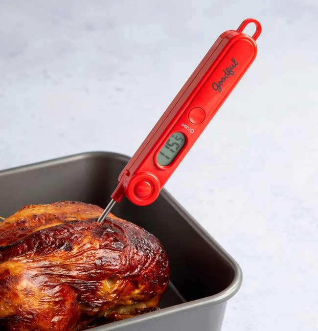 The meat thermometer in chicken with a reading of 115.5 degrees displayed on the front