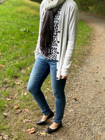 reviewer wearing jeans and a cardigan, plus black basic ballet flats
