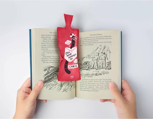 Hands holding an open book with a red whoopie cushion bookmar