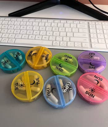 reviewer photo of the colorful pill compartments next to a keyboard