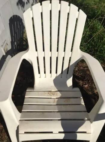 Plastic Adirondack seat  with a shadiness   formed  connected  it, positioned outdoors adjacent   a wall
