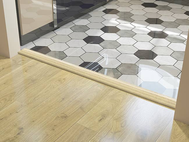 the vinyl floor strip installed on a threshold between rooms where one floor is tile and the other is vinyl