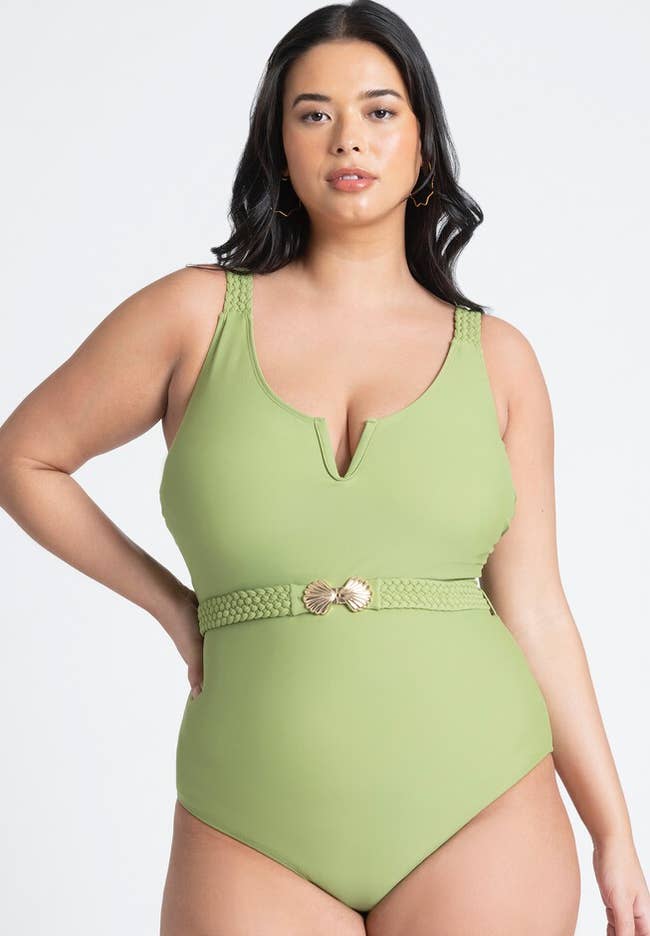 Woman models olive green one-piece swimsuit with a belted waist