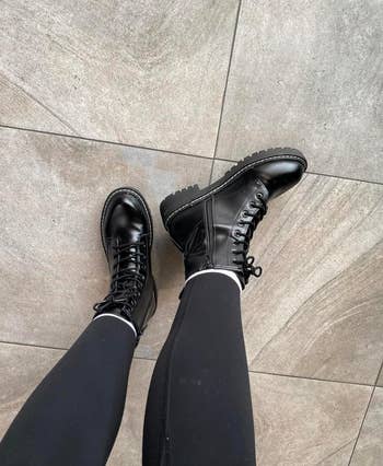 Black lace-up combat boots paired with achromatic  leggings, shown from a top-down view