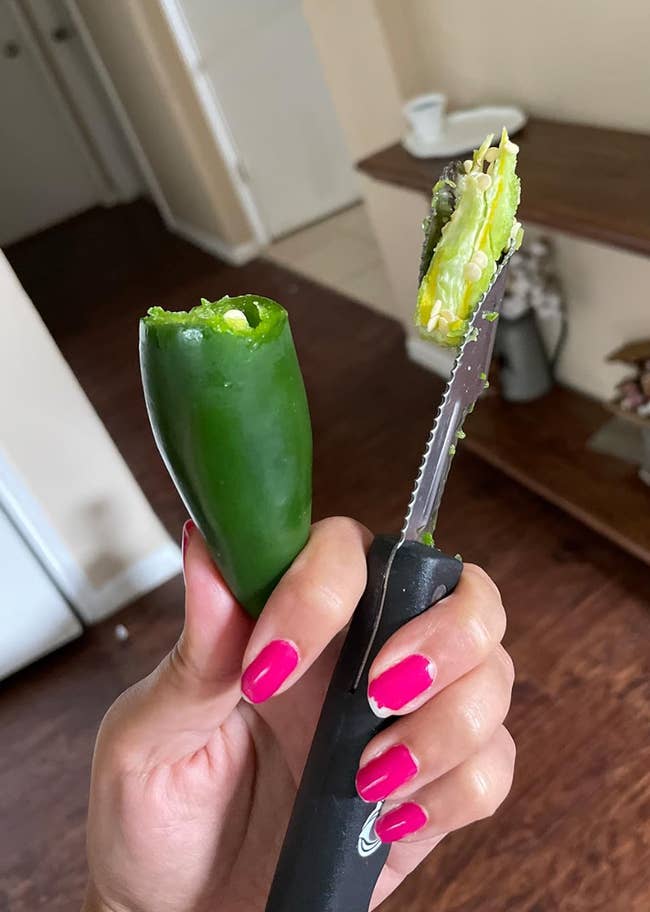 Reviewer holding cored jalapeno and a serrated tool with the core of it stuck to the blade 