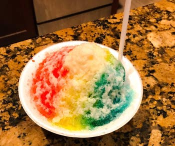 A bowl of shaved ice with multiple syrup flavors, on a countertop