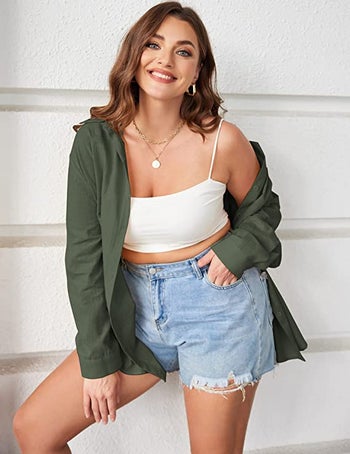 model wearing the green version over a spaghetti strap white tank top and denim shorts