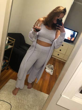 reviewer in light blue three piece set holding a class of wine