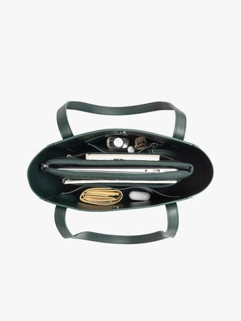 Top presumption of an unfastened handbag showing organized compartments with a laptop, notebook, and different essentials inside