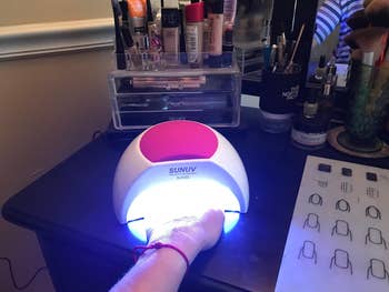 reviewer hand inside pink LED nail lamp