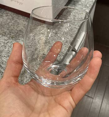 reviewer holding one of the empty stemless wineglasses