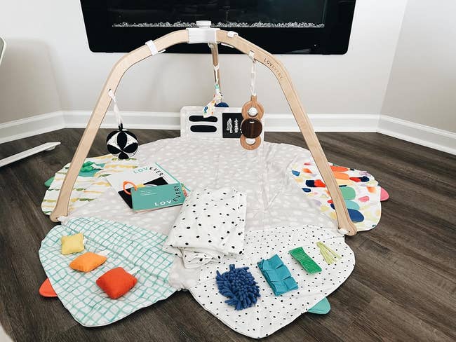 reviewer's babe play gym with plush toys and assorted colorful sensory blankets and pillows