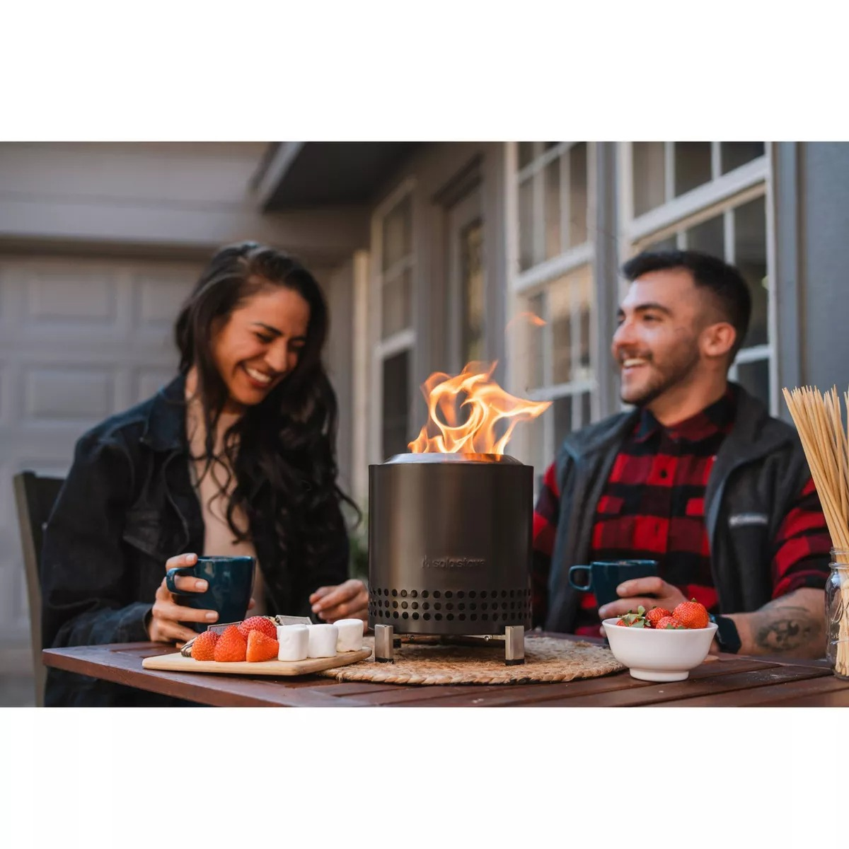 A mates  enjoying drinks astir   a tabletop occurrence  pit with effect   bowls connected  a patio, suggesting a cozy outdoor setting