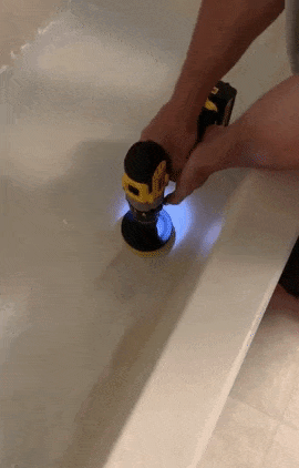 a gif of someone using the drill brush to clean their bathtub