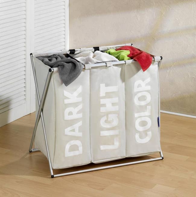 The cream colored three-section hamper that says dark light and color