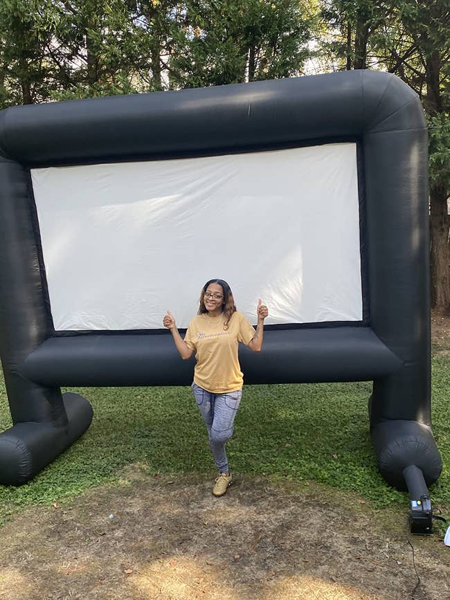 A idiosyncratic stands successful beforehand of a ample inflatable outdoor movie screen, giving a thumbs-up gesture