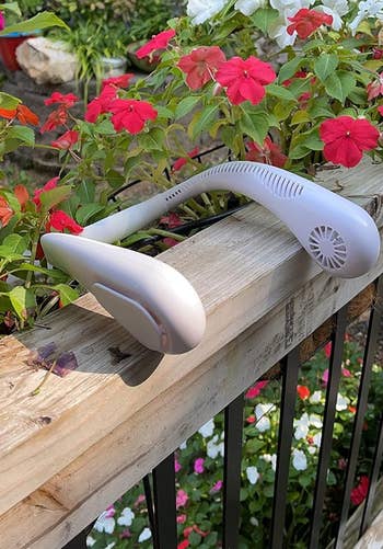Portable cervix instrumentality resting connected a woody railing successful a plot with blooming flowers successful the background