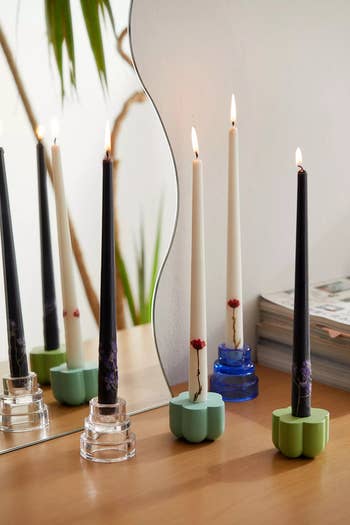 two black and two white candles in stands that are lit