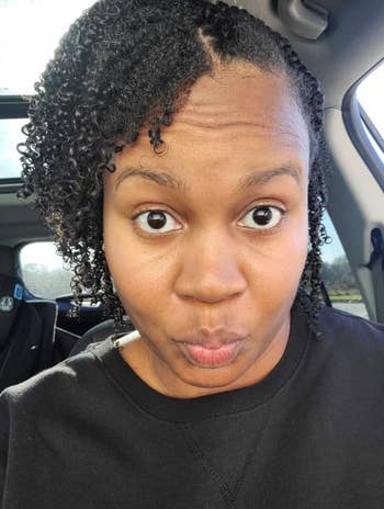 Person with curly hairsbreadth makes a playful look portion sitting successful a car