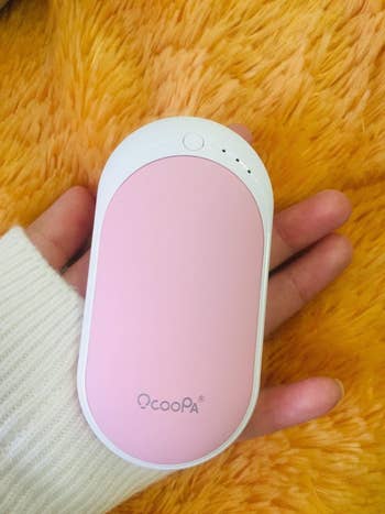 Reviewer holding the hand warmer in the pink color