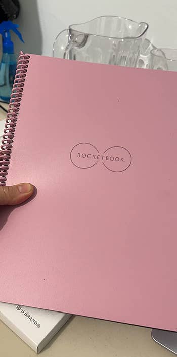 Reviewer holding their reusable notebook with a pink cover