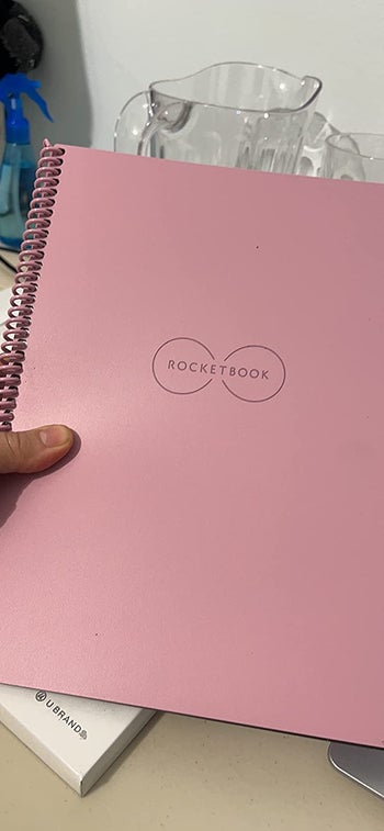 Reviewer holding their reusable notebook with a pink cover