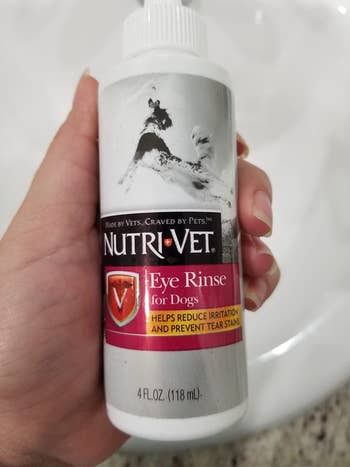 reviewer's hand holding up bottle of eye rinse