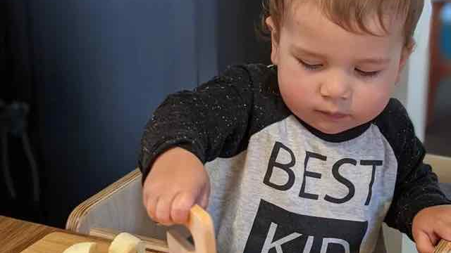 Reviewer's photo of their child cutting a banana with the maple wood chopper
