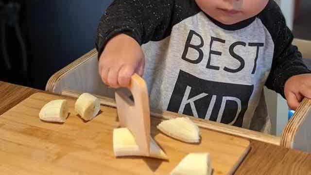 Reviewer's photo of their child cutting a banana with the maple wood chopper