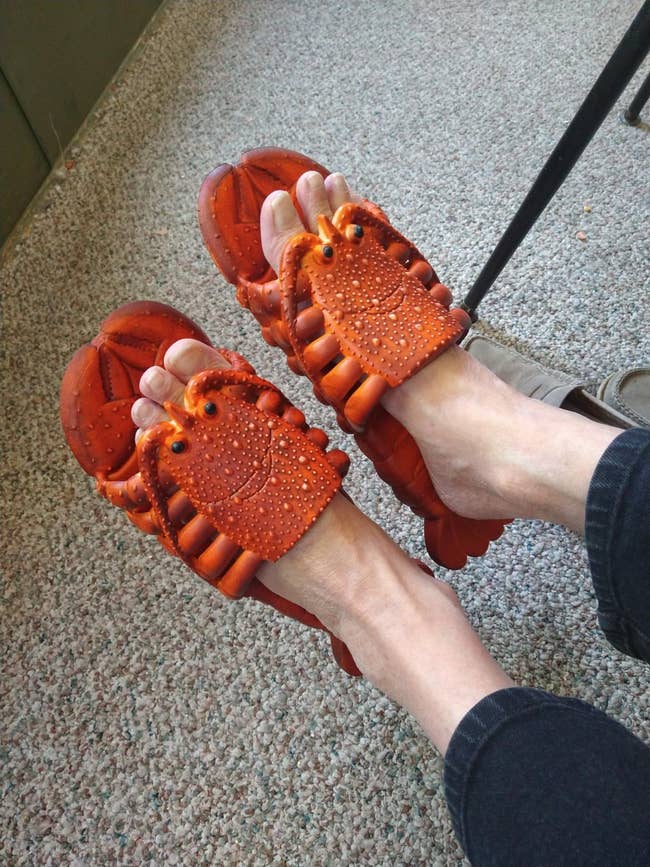 Person wearing playful crab-shaped sandals, indoors, with jeans