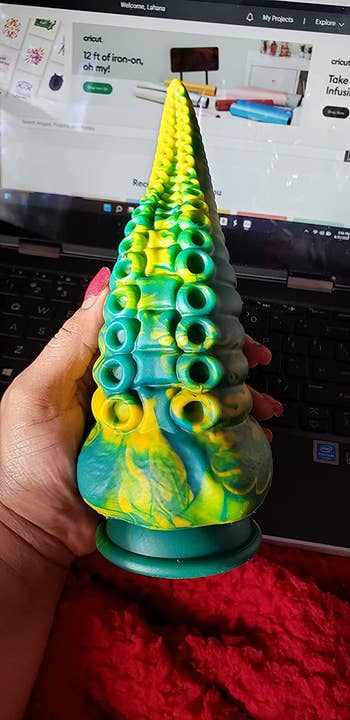 Reviewer holding green and blue multicolor tentacle dildo