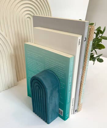 teal book end holding up stack of books