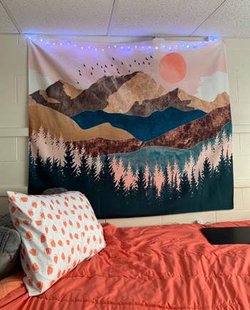 another reviewer with the tapestry hanging above their bed with string lights 