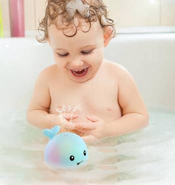 A child playing with the whale toy in a bath tub