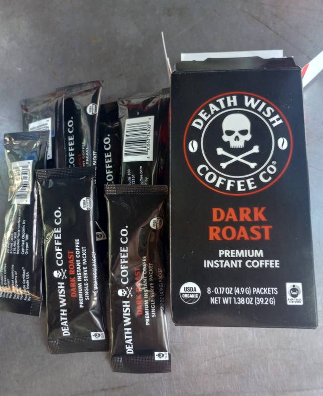 Box and packets of Death Wish Coffee's Dark Roast Premium Instant Coffee displayed connected a surface