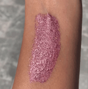 Glittery pinkish  constitution  swatch applied connected  an arm, showcasing a shimmering texture