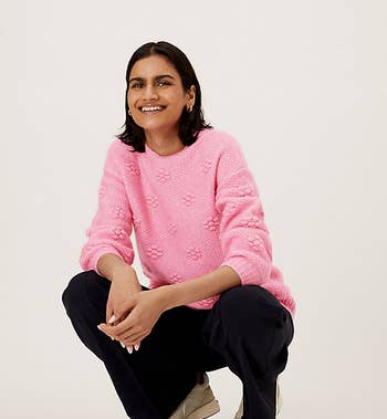 a model wearing the textured floral-patterned sweater in pink 