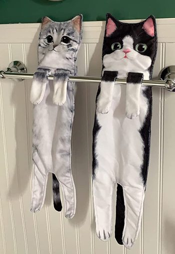 Gray and black cat versions on a metal shelf in a bathroom 