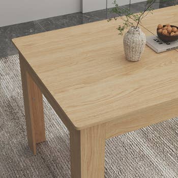Wooden eating array with a woven vase and nuts connected a book, placed connected a textured rug, perfect for modern location decor shopping