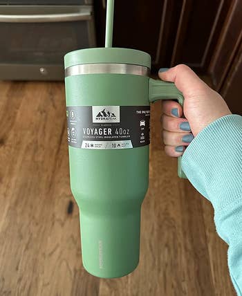 reviewer holding the green tumbler to show its tapered design